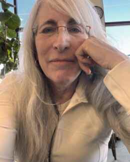 Dina Paul, resting her chin on her hand, in the light of a café window